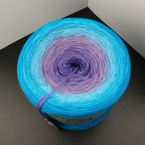 May include: A ball of yarn with a gradient of blue, light blue, and purple colors. The yarn is wound into a ball shape and is ready to be used for knitting or crocheting.