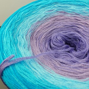 May include: A skein of yarn in a gradient of light blue, turquoise, and lavender colors. The yarn is wound into a ball shape.