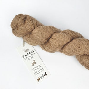 May include: A skein of brown yarn labelled "GAZZAL BABY ALPACA Powe Colos" with a tag that reads "55% Baby Alpaca 45% Merino Wool 100 g - 3.52 oz ca. 320 mt - 349 yd".