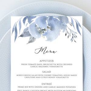 Puede incluir: Un menú de boda azul y blanco con un diseño floral de acuarela. El menú incluye opciones de aperitivo, ensalada, plato principal y postre. El texto dice: "Menú", "Aperitivo", "Bruschetta de tomate fresco y albahaca con vinagreta balsámica de ajo triturado", "Ensalada", "Ensalada de verduras mixtas con tomates cherry, crutones caseros y vinagreta de miel cítrica", "Plato principal", "Costilla de primera con cebolla y puré de patatas con ajo", "Pechuga de pollo de corral con champiñones y risotto de parmesano", "Salmón con salsa de mantequilla de limón y perejil fresco", "Postre", "Pastel de boda", "Cheesecake con fresas"
