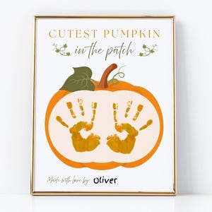 May include: A framed print featuring a pumpkin design with handprints inside. The text "Cutest Pumpkin in the Patch" is above the pumpkin, and "Made with love by: Oliver" is below. The pumpkin is orange with a green stem.