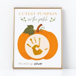 May include: A framed print featuring an orange pumpkin with a handprint in the center. The text "Cutest Pumpkin in the Patch" is above the pumpkin, and "Made with love by: Oliver" is below.