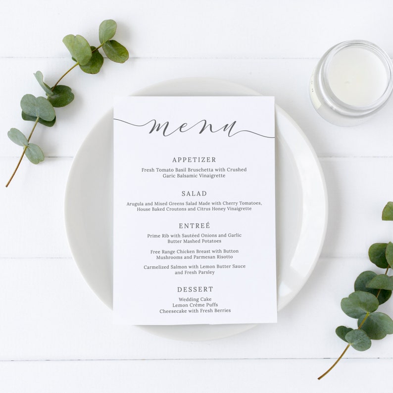 May include: A white menu with a black handwritten word "menu" at the top. The menu lists appetizers, salad, entree, and dessert options. The menu is on a white plate with a white background.