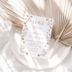 May include: A floral bridal shower invitation with the text "LOVE in bloom" and "Samantha Lowell". The invitation includes the date, time, location, and RSVP information. It also mentions that the bride-to-be is registered at Target and Amazon.