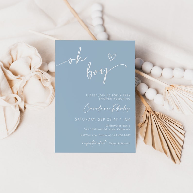 Może przedstawiać: Zaproszenie na baby shower z jasnoniebieskim tłem. Tekst "oh boy" jest napisany kursywą, z dodatkowym tekstem poniżej. Zaproszenie zawiera szczeg&oacute;ły, takie jak imię osoby honorowanej, data, godzina i miejsce.