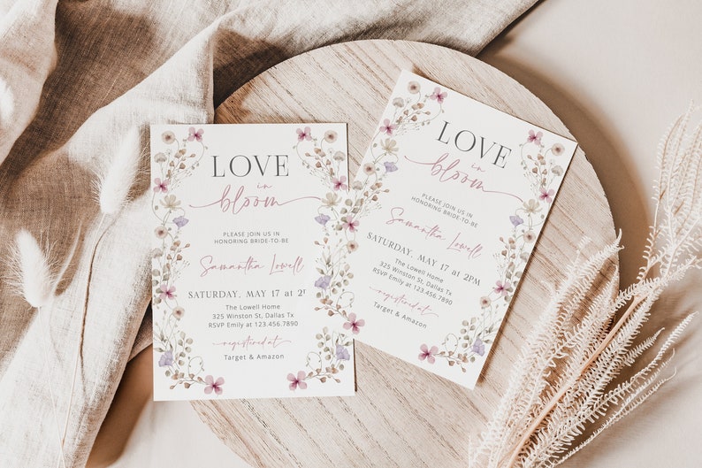 May include: Two floral-themed bridal shower invitations with the text "LOVE in bloom" and the bride-to-be's name, Samantha Lowell. The invitations are on a wooden surface with a beige fabric in the background.