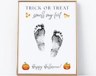 May include: A rectangular framed print with a white background featuring the black text TRICK OR TREAT smell my feet and Happy Halloween. The design includes two black baby footprints in the center, orange candy corn, and two orange jack-o'-lanterns.