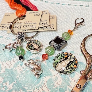 May include: A silver charm with a bunny rabbit design, a green glass bead, and a black bead. The charm is attached to a silver key ring with a silver clip. The key ring is also attached to a small card that reads "Weeks Dye Works" and "Specializing in Hand Dyed Fibers".