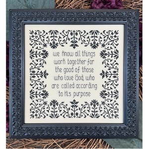 May include: Black and white cross-stitch embroidery framed in a black wood frame. The embroidery features a floral border and the text "we know all things work together for the good of those who love God, who are called according to His purpose".