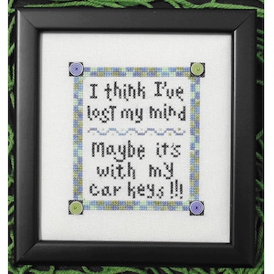 Könnte beinhalten: Ein gerahmtes Kreuzstichbild mit weißem Hintergrund und schwarzem Rahmen. Der Kreuzstich zeigt ein grünes, blaues und weißes Karomuster mit dem Text "I think I've lost my mind maybe it's with my car keys!!"