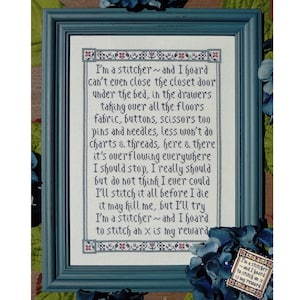 May include: A framed cross-stitch design with a poem about a stitcher who hoards fabric, buttons, scissors, pins, needles, charts, and threads. The poem reads, "I'm a stitcher -- and I hoard can't even close the closet door under the bed, in the drawers taking over all the floors fabric, buttons, scissors too pins and needles, less won't do Charts & threads, here & there it's overflowing everywhere I should stop, I really should but do not think I ever could I'll stitch it all before I die it may hill me, but I'll try I'm a stitcher -- and I hoard to stitch ah x is my reward"