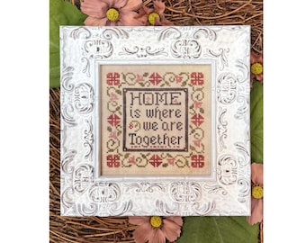 May include: A white framed cross-stitch with a floral border and the text "HOME is where we are Together".