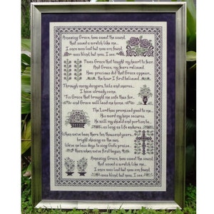 May include: A framed cross-stitch embroidery with a purple background and a white fabric with black text. The text is a poem titled "Amazing Grace" and includes the lyrics: "Amazing Grace, how sweet the sound that saved a wretch like me... I once was lost but now am found was blind but you, I see."