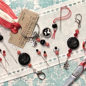 May include: A set of embroidery floss, needles, and a needle minder with a black and white bird design. The needle minder is attached to a silver keyring. The set also includes a pair of red and white scissors with a floral design.