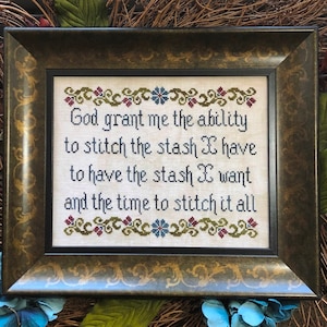 以下が含まれることがあります： 白い背景に茶色、緑、青の刺繍が施された、額装されたクロスステッチ。テキストは「神様、私が持っている在庫を縫う能力、欲しい在庫を持つこと、そしてすべてを縫う時間を与えてください。」です。
