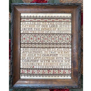 May include: Framed cross-stitch artwork with a religious quote. The text, in shades of brown and red, reads "Praise be to the God and Father of our Lord Jesus Christ." The frame is a dark, ornate wood.