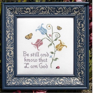 May include: A framed cross-stitch embroidery with a floral design and the text "Be still and know that I am God".