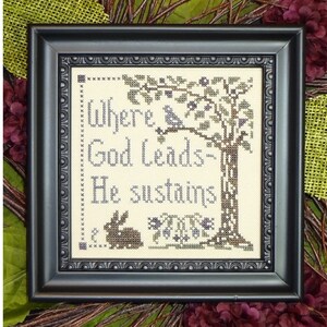 May include: A framed cross-stitch embroidery with a tree, a bird, and a rabbit. The text reads "Where God Leads - He sustains".