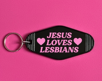 May include: Black keychain with a pink heart on each side and the text "JESUS LOVES LESBIANS" in white.