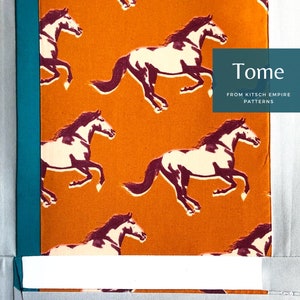 May include: A close-up of a fabric with a repeating pattern of white and purple horses running on an orange background. The fabric is framed with teal and gray fabric. The text "Tome from Kitsch Empire Patterns" is printed on the fabric.