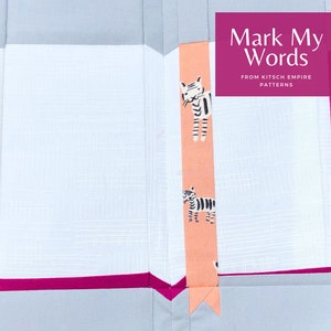 Puede incluir: Un libro de tela rosa y blanco con un marcapáginas de tela rosa con estampado de cebra en blanco y negro. La portada del libro tiene el texto "Mark My Words" y "From Kitsch Empire Patterns".