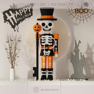 May include: A Halloween-themed papercraft skeleton figure wearing a top hat and holding a pumpkin-topped staff. The skeleton is dressed in orange and black, with a white skeleton design. The words "Happy Halloween" are visible.