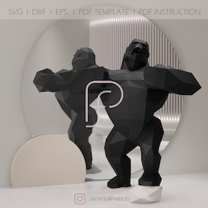 May include: A black papercraft model of a gorilla in a dynamic pose, standing on a white base. The model is made up of many polygons, giving it a geometric look. The gorilla is roaring with its mouth open, showing its teeth. The model is set against a white background with a circular mirror behind it.