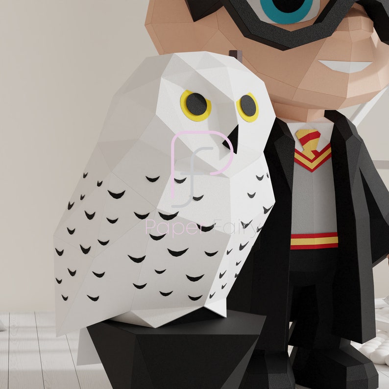 Close-up of a low poly papercraft snowy owl with yellow eyes and black feather markings, standing next to the wizard figure. Part of a printable DIY papercraft template with digital files for easy crafting.