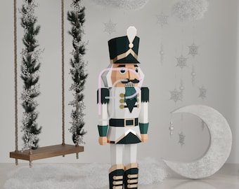 Pode incluir: Uma figura de quebra-nozes de papel branco e verde com detalhes dourados e um bigode preto. O quebra-nozes está em pé sobre uma superfície branca com uma lua crescente branca e um balanço de madeira no fundo.