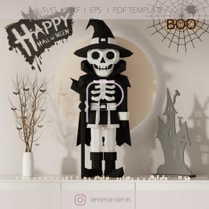 May include: A paper skeleton wearing a black witch hat and cape, perfect for Halloween decor. The skeleton has a white rib cage and is standing in front of a large, round, cream-colored moon. The words "Happy Halloween" are written in black.