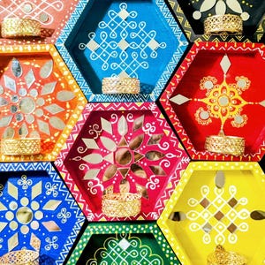 May include: A collection of colorful, hexagonal wooden shelves with intricate designs and mirrored accents. Each shelf is painted in a different vibrant color and holds a decorative gold-colored item. The shelves are arranged in a grid pattern.