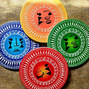 May include: Four round decorative plates with intricate designs. Each plate features a different color background: blue, green, red, and yellow. The plates are decorated with white and black geometric patterns and depict figures engaged in various activities.