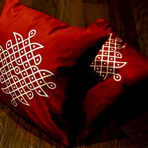May include: Two red throw pillows with white geometric designs. The pillows are made of a soft, velvety fabric.