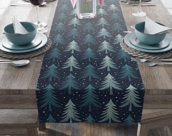 Puede incluir: Un camino de mesa azul marino con un patrón repetido de árboles de Navidad turquesa y plateados y puntos blancos. El camino de mesa está colocado sobre una mesa de madera con cuencos, platos y copas de vino turquesas.