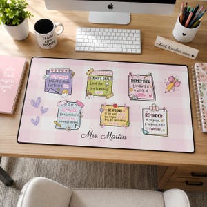 May include: A rectangular desk mat with a light pink and white checkered pattern featuring six illustrated sticky notes with inspirational teacher-themed text, small decorative doodles, and the name Mrs. Martin printed in black script at the bottom.