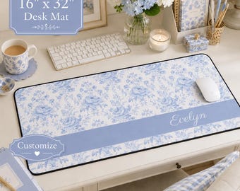 May include: A rectangular desk mat measuring 16 inches by 32 inches, featuring a white and blue floral pattern. A solid light blue horizontal band runs across the lower section, displaying the name Evelyn in white script text.
