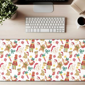 Op de afbeelding: Een rechthoekige bureaumat met een feestelijk kerstpatroon. Het ontwerp bevat peperkoekenmannetjes, notenkrakers, sneeuwpoppen, teddyberen en zuurstokken op een witte achtergrond. De mat is ongeveer 80 cm lang en 30 cm breed.