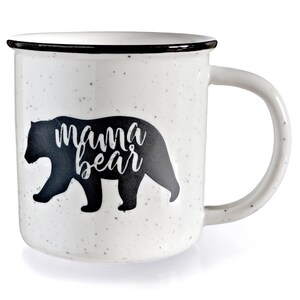 May include: White ceramic mug with a black silhouette of a bear and the text "mama bear" printed on it. The mug has a black rim and a speckled finish.