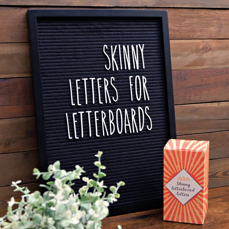 May include: A black letter board with the text "SKINNY LETTERS FOR LETTERBOARDS" in white letters. A box of letterboard letters with a red, yellow, and gold design is in the foreground. The box has the text "Skinny letterboard letters" in white letters.