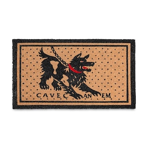 May include: A rectangular tan doormat with a black border and a black polka dot pattern. The center features a black dog illustration wearing a red collar and attached to a chain, with the text CAVE CANEM printed in black capital letters below.
