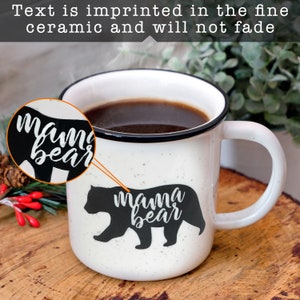 May include: White ceramic mug with a black rim and handle. The mug has a black silhouette of a bear with the text "mama bear" printed in white on it.