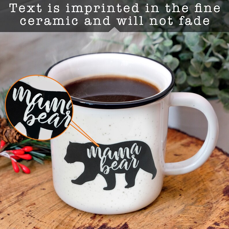 May include: White ceramic mug with a black rim and handle. The mug has a black silhouette of a bear with the text "mama bear" printed in white on it.