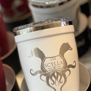 White stainless steel tumbler with silver SCYLLA ANIMATION TEAM logo, featuring a mythical creature and octopus tentacles. Perfect for coffee, tea, or any beverage. Ideal gift for animation fans.