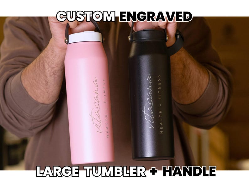 Custom engraved large tumbler with handle. Stainless steel water bottle, pink and black, with 'Vitasana Health + Fitness' logo. Ideal for gym, travel, and daily hydration.