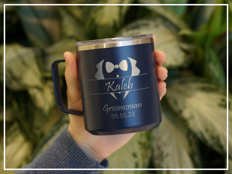 Personalized navy blue tumbler for a groomsman, featuring laser-engraved name Kaleb and Groomsman 05.05.22 with a bow tie design. Insulated, stainless steel mug for wedding parties.