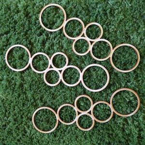 May include: A set of wooden circles of varying sizes, arranged in a pattern on a green carpet. The circles are all made of the same type of wood and have a natural finish.