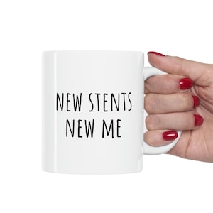 May include: White ceramic coffee mug with black text that reads "NEW STENTS NEW ME".