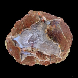 Puede incluir: Una gran geoda de ágata con un interior cristalino blanco y un exterior marrón rojizo. La geoda tiene una forma redonda y lisa y mide aproximadamente 25 cm de diámetro.