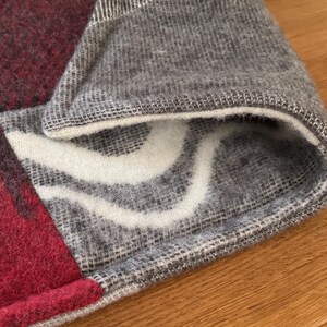 Close-up texture of the rich, deep maroon/red wool square on the checkered pet mat.
