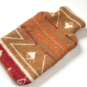 Brown geometric wool hot water bottle cover with angled zigzag lines and burgundy corner detail on white background